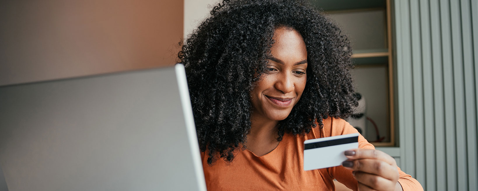 woman with credit card smiling and looking at laptop