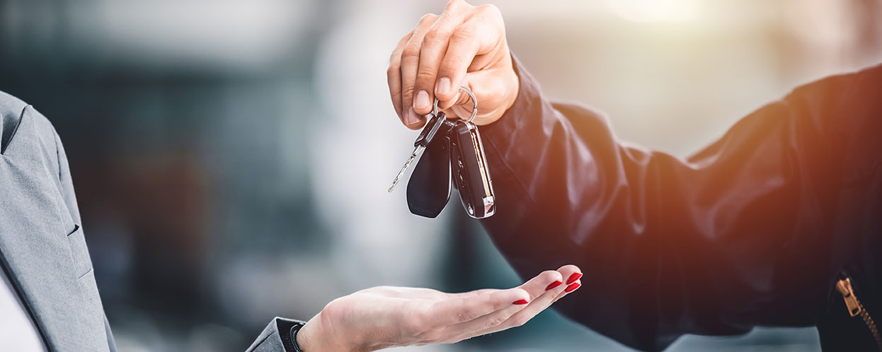 Hands passing off car keys to other set of hands